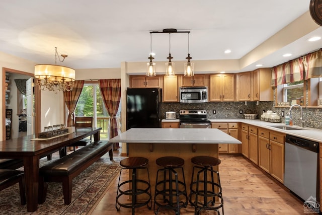 kitchen featuring pendant lighting, sink, light wood-type flooring, appliances with stainless steel finishes, and a notable chandelier