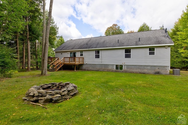 rear view of property with a yard, a fire pit, central AC unit, and a deck