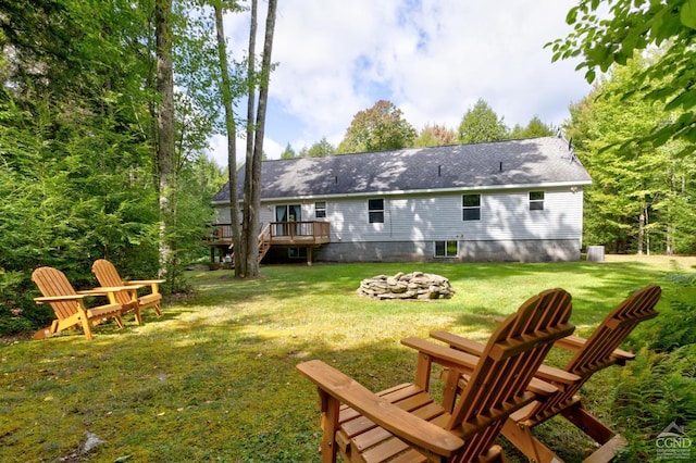 rear view of property featuring a lawn, a deck, and an outdoor fire pit