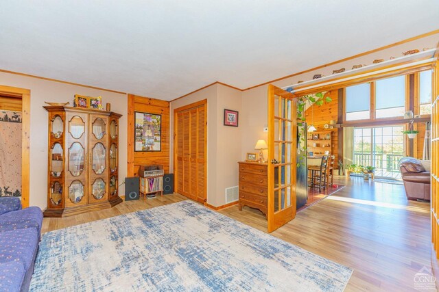 living room featuring high vaulted ceiling, a wood stove, wooden walls, and light hardwood / wood-style flooring