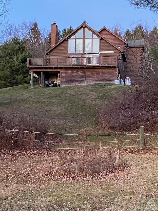 back of property featuring a wooden deck and a yard