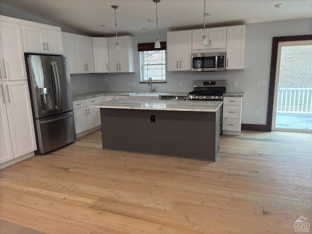 kitchen with a center island, white cabinets, hanging light fixtures, light hardwood / wood-style flooring, and appliances with stainless steel finishes