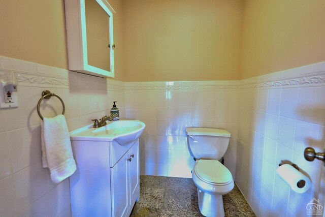 bathroom with vanity, toilet, and tile walls