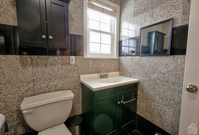 bathroom with vanity, toilet, and tile walls