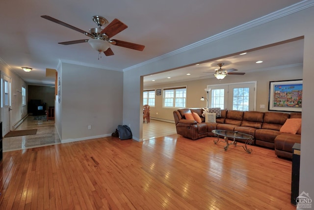 living room featuring a baseboard heating unit, light wood-type flooring, and crown molding