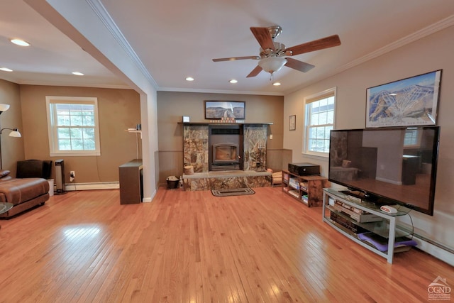 living room featuring a fireplace, a baseboard radiator, a wealth of natural light, and ornamental molding