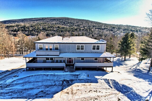 snow covered back of property featuring a mountain view