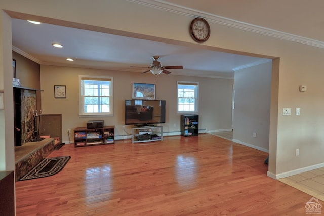 living room featuring a fireplace, light hardwood / wood-style floors, a wealth of natural light, and ornamental molding