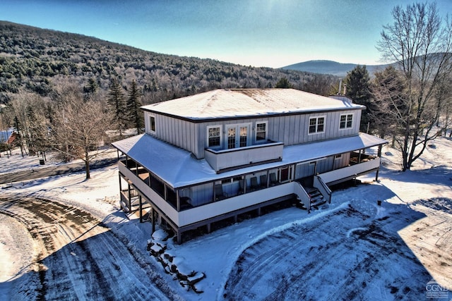 snow covered back of property featuring a mountain view