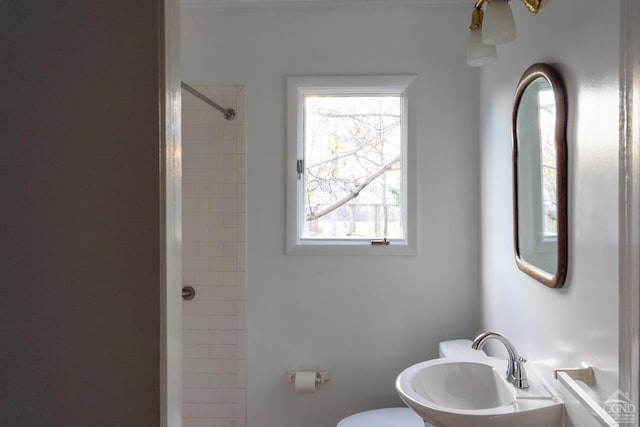 bathroom with a tile shower, toilet, and sink