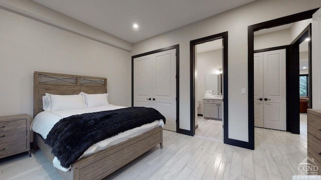 bedroom featuring multiple closets, light hardwood / wood-style flooring, and ensuite bath