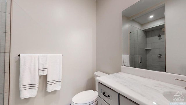 bathroom with toilet, an enclosed shower, and vanity