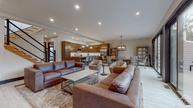 living room featuring beamed ceiling, a notable chandelier, and light wood-type flooring