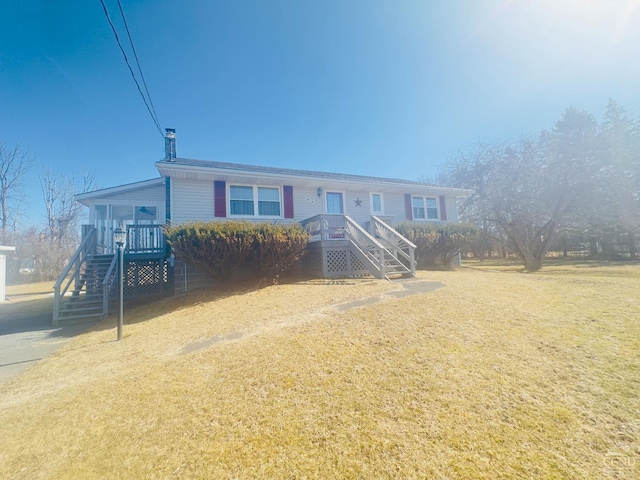 view of front of home with a chimney, stairs, and a front lawn