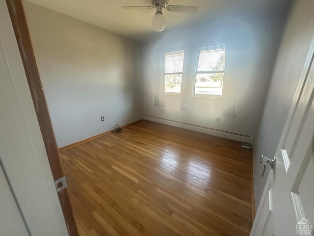 unfurnished room with baseboard heating, a ceiling fan, baseboards, and wood finished floors