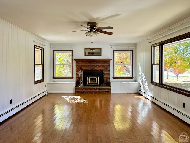 unfurnished living room featuring hardwood / wood-style flooring, ceiling fan, crown molding, and baseboard heating