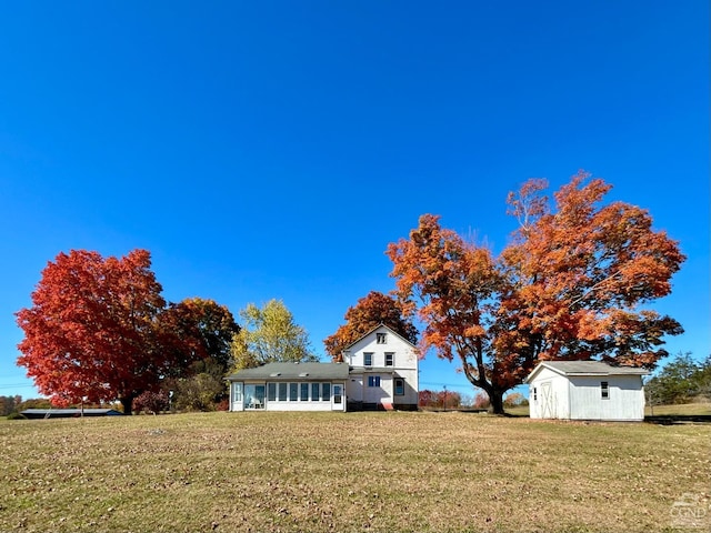 view of front of property featuring a storage shed and a front yard