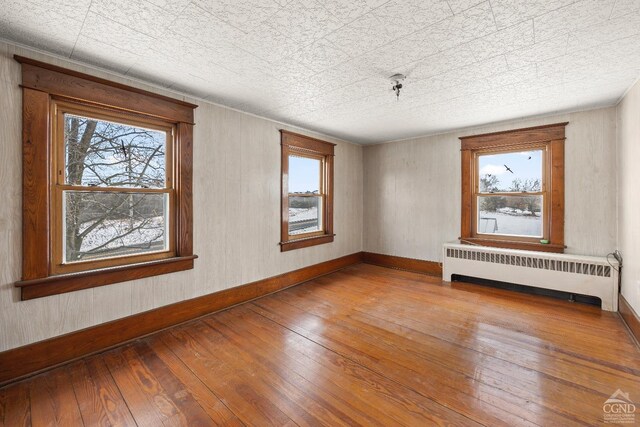 unfurnished room with hardwood / wood-style flooring and radiator