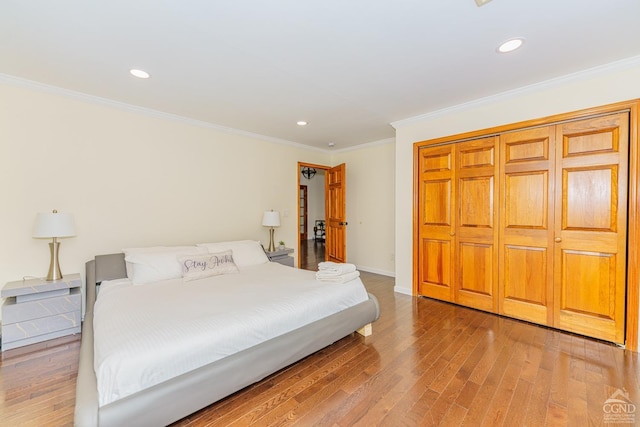 bedroom featuring wood-type flooring, crown molding, and a closet