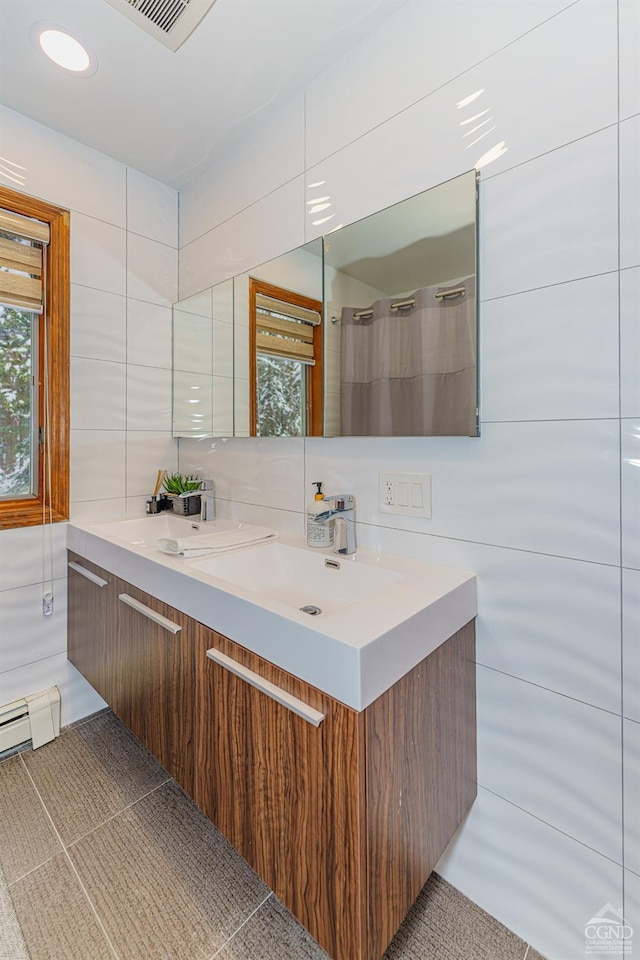 bathroom featuring vanity, backsplash, tile patterned floors, baseboard heating, and tile walls