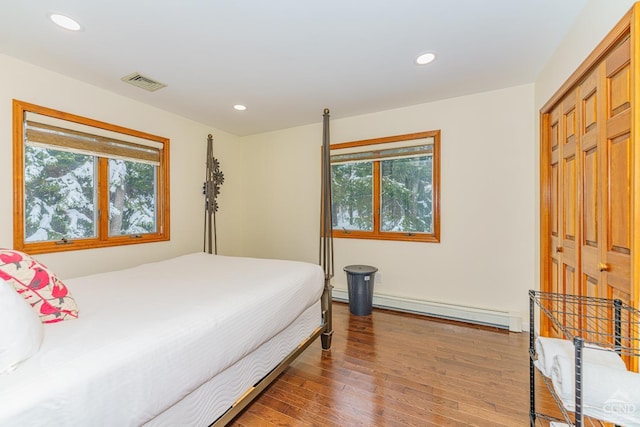 bedroom featuring wood-type flooring, a baseboard radiator, and a closet