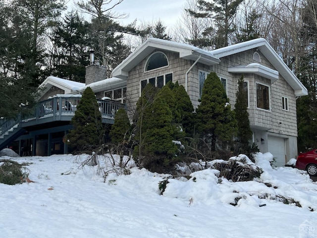 view of snowy exterior with a deck and a garage