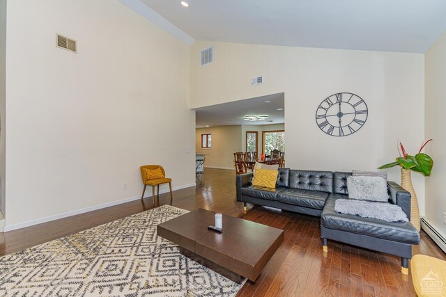 living room featuring baseboard heating, high vaulted ceiling, and wood-type flooring