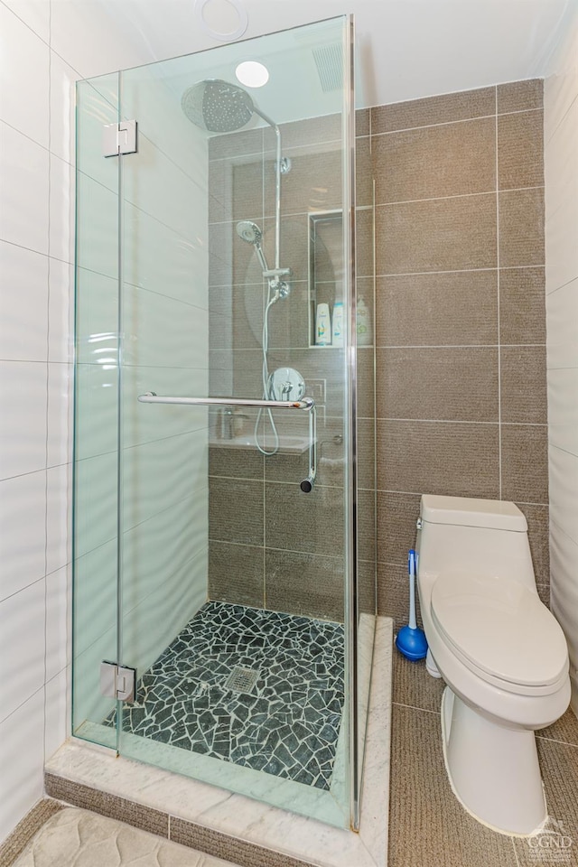 bathroom featuring tile patterned flooring, tile walls, and a shower with shower door