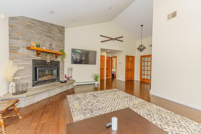 living room with ceiling fan, dark hardwood / wood-style flooring, high vaulted ceiling, a baseboard heating unit, and a fireplace