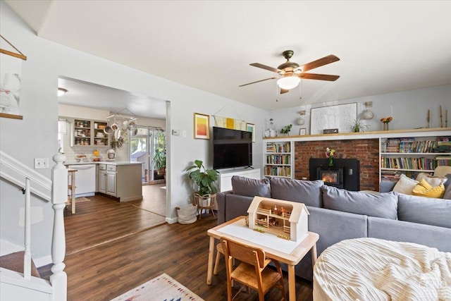 living room featuring ceiling fan, a wood stove, and dark wood-type flooring