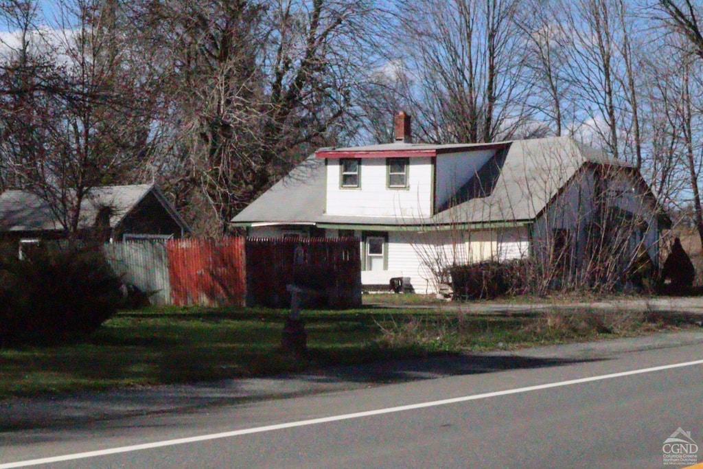 view of front facade with a chimney and fence