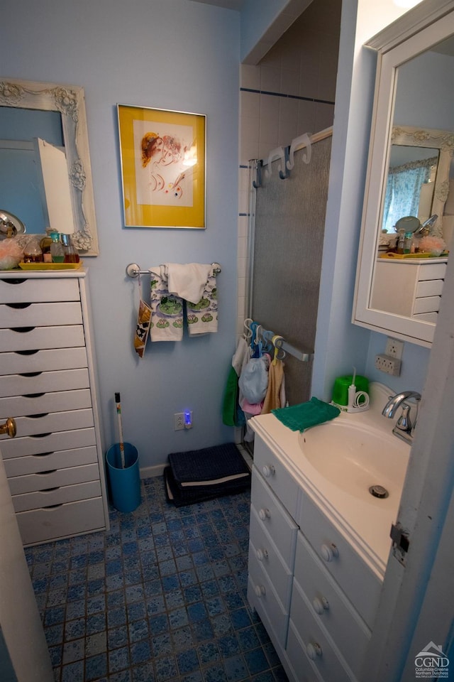 bathroom with a tile shower and vanity