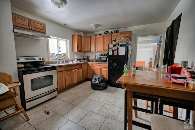 kitchen featuring range with electric stovetop, black fridge, and light tile patterned floors