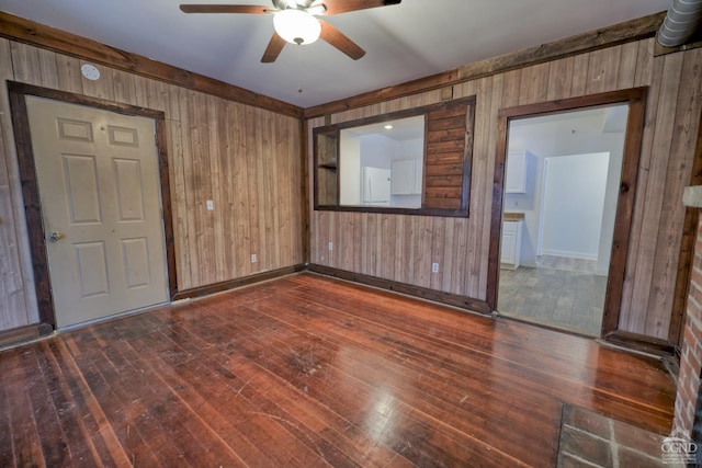 spare room featuring wooden walls, ceiling fan, and dark hardwood / wood-style floors