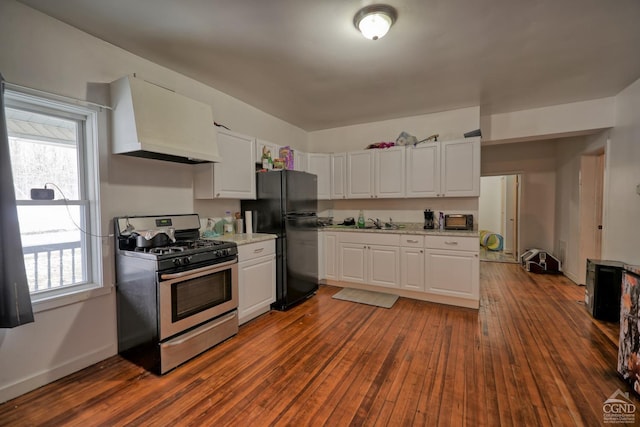 kitchen with ventilation hood, black refrigerator, stainless steel gas stove, dark hardwood / wood-style flooring, and white cabinetry