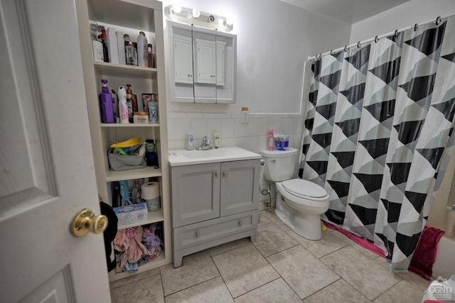 bathroom with a shower with curtain, tile patterned floors, toilet, vanity, and tile walls