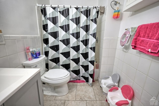 full bathroom with tile patterned flooring, toilet, shower / tub combo with curtain, vanity, and tile walls