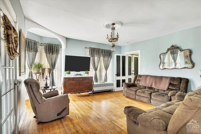 living area featuring radiator heating unit, hardwood / wood-style flooring, and plenty of natural light