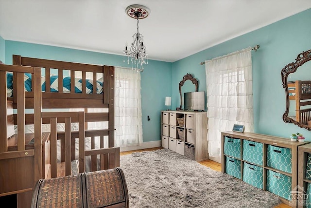 bedroom featuring wood finished floors, a notable chandelier, and multiple windows