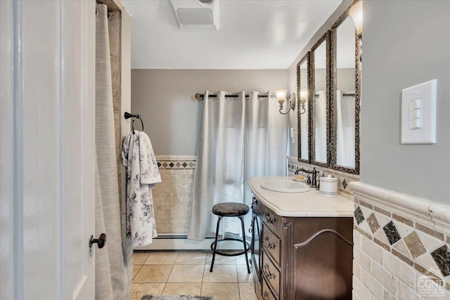 full bath with tile patterned floors, wainscoting, a baseboard heating unit, and vanity