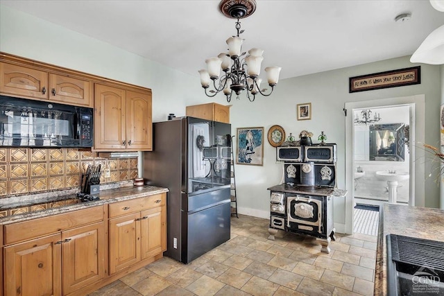 kitchen with stone finish floor, tasteful backsplash, a chandelier, baseboards, and black appliances