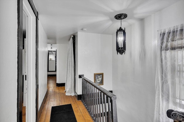 hall featuring an upstairs landing, hardwood / wood-style floors, and a notable chandelier
