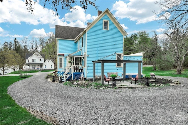back of house featuring a gazebo, a shingled roof, and a chimney