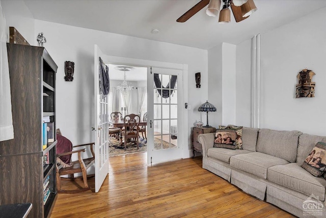 living room with light wood-style flooring and ceiling fan with notable chandelier