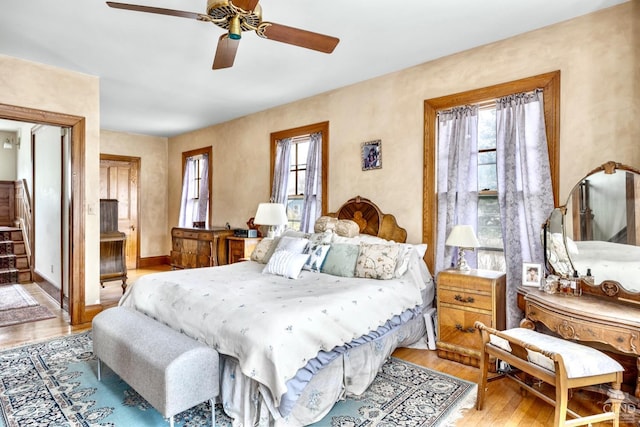 bedroom with light wood-type flooring, multiple windows, and ceiling fan