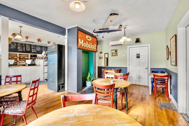 dining space with wood-type flooring and a wall mounted AC