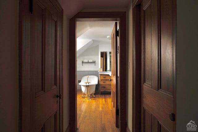 hallway featuring light wood-type flooring and vaulted ceiling