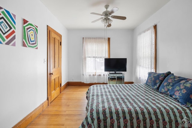 bedroom featuring ceiling fan, light hardwood / wood-style floors, and multiple windows