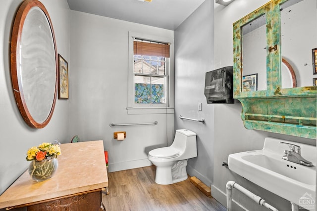 bathroom with toilet, sink, and hardwood / wood-style flooring