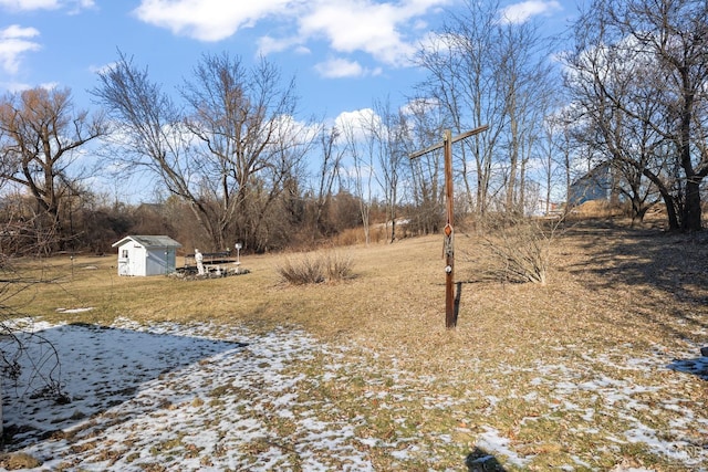 snowy yard featuring a storage unit and an outbuilding